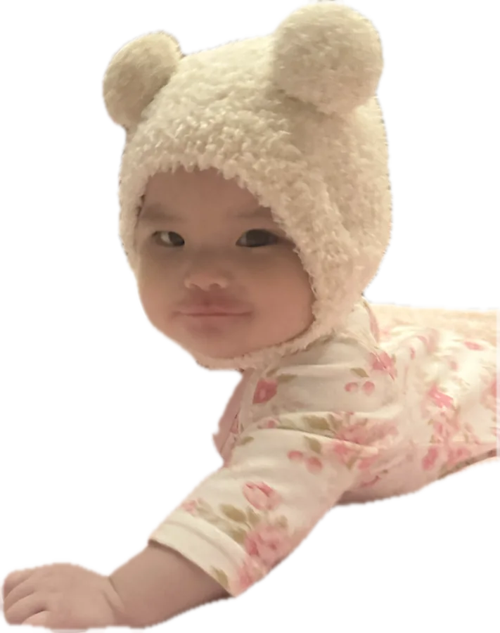 Aria lying on her tummy, smiling sideways at the camera
